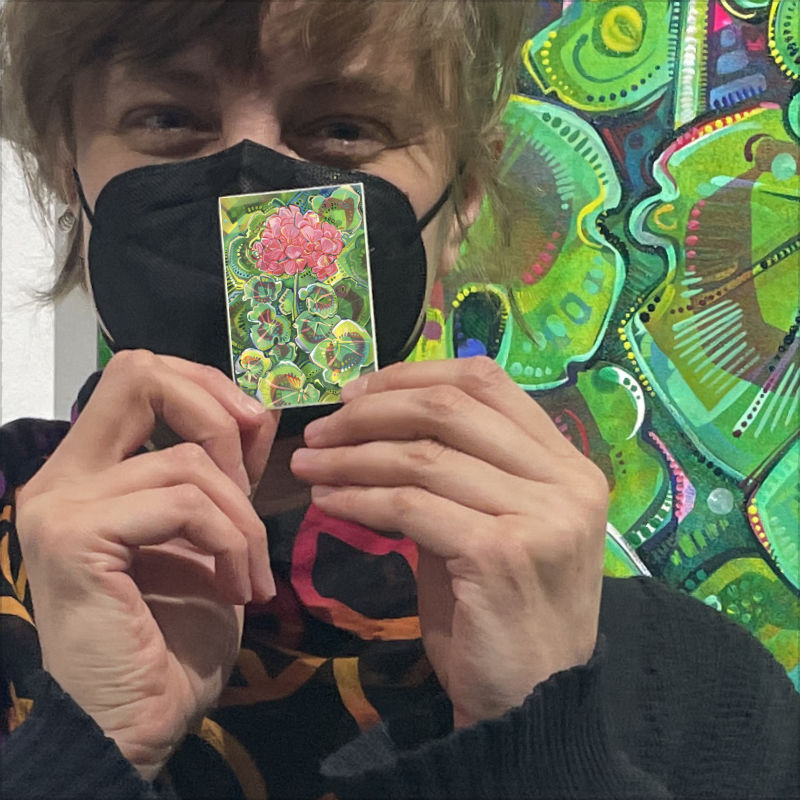 Gwenn Seemel with their geranium painting and a sticker version of the image